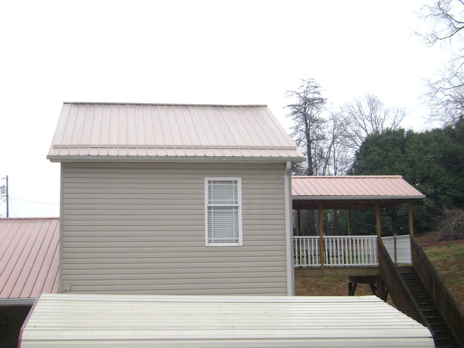 Tan metal roofs on a two story addition and attached porch, from a Roof Replacement job in Del Mar