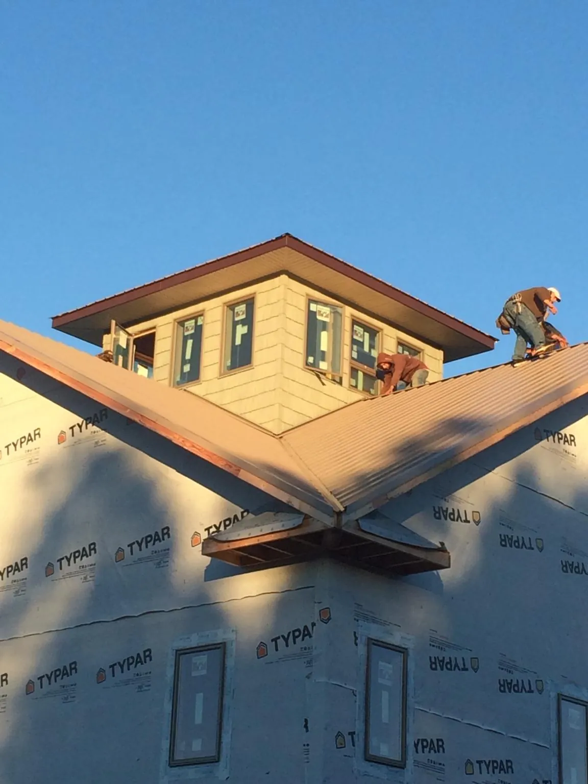 Roofers working around a rooftop cupola on a new metal roof at sunset — Roof Waterproofing in Del Mar by Roofing Brothers